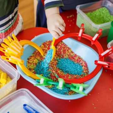 Kids playing with sand and toys around sensory table