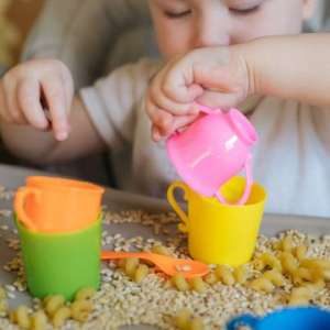 child pouring beans from jug to jug